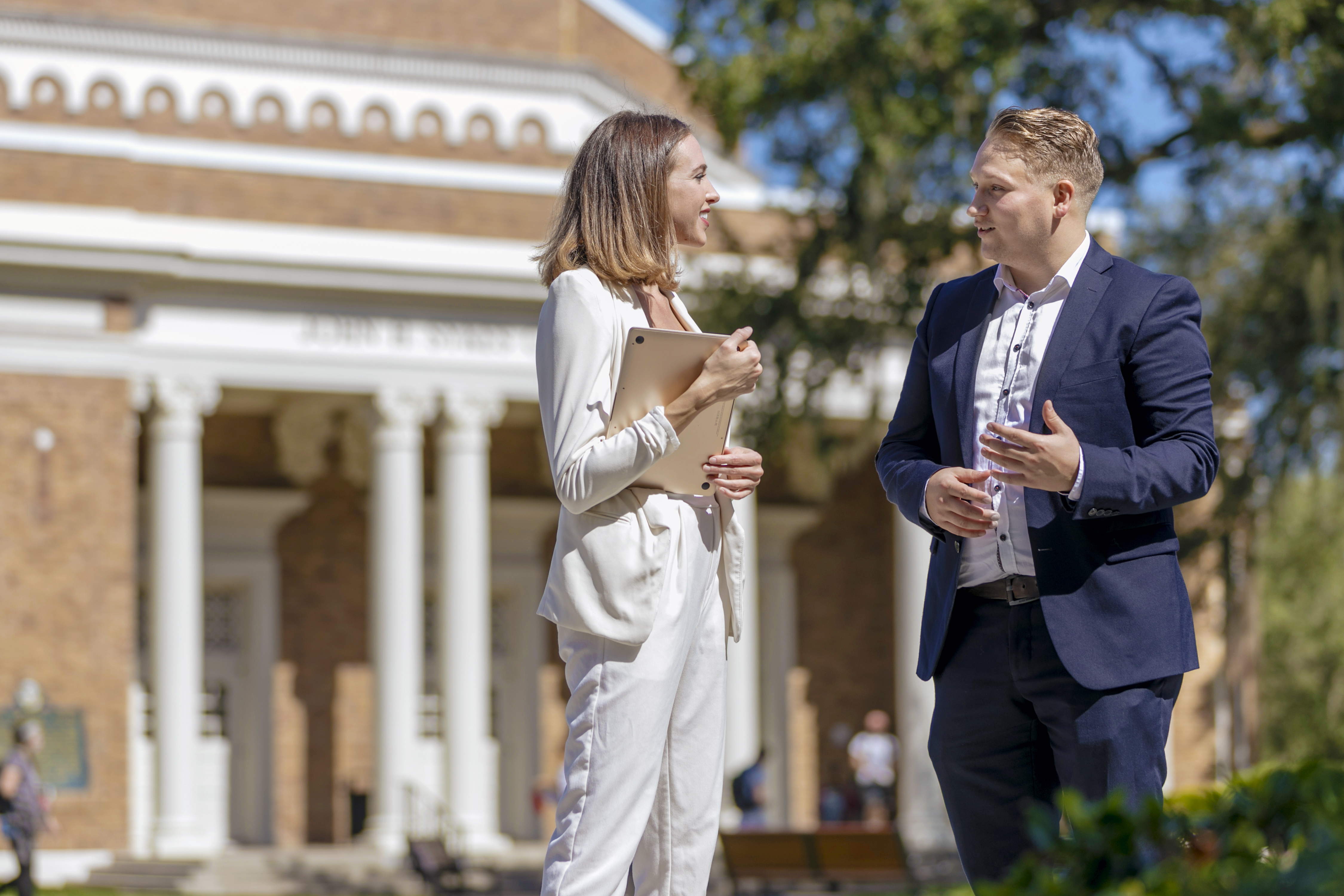 Two student talking in front of the College of Business.