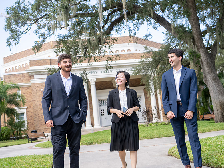 Students dressed professionally walking in front of hte college of business